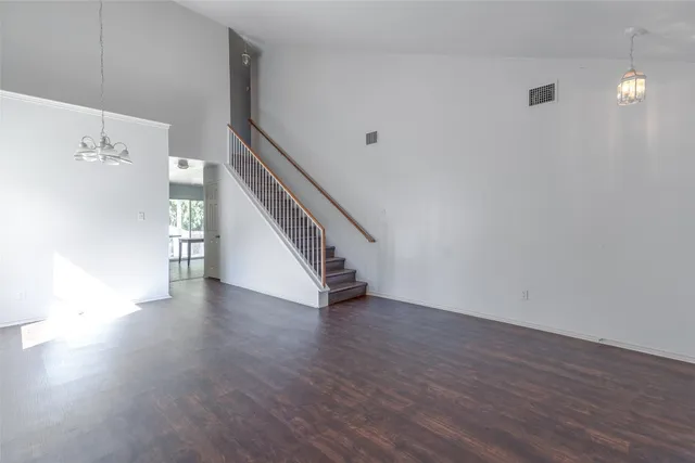 a view of an empty room with wooden floor and stairs