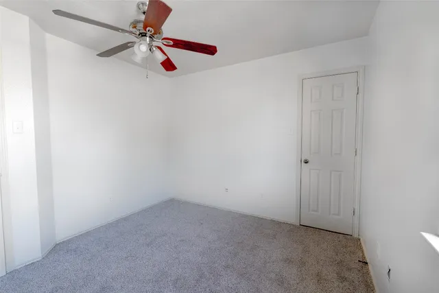 an empty room with a fan & a window