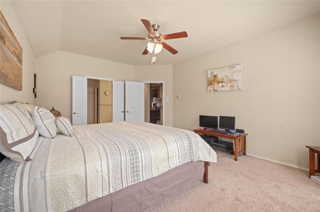 520 Rustic Oak Lane McKinney, TX 75072 - Photo 15 of 30 Bedroom featuring a vaulted ceiling with a ceiling fan, neutral wall paint, carpet flooring, and two white bi-fold doors