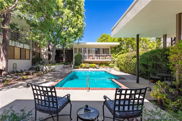 a patio with a table and chairs and potted plants