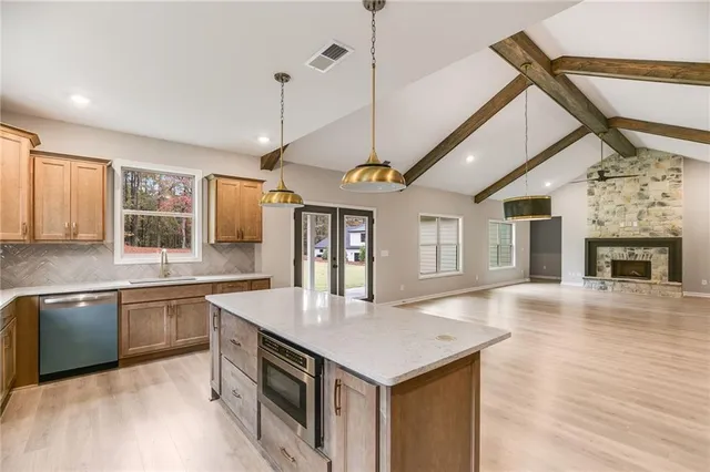a kitchen with a stove center island a sink cabinets and wooden floor