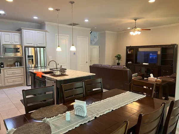 a kitchen with a dining table chairs and refrigerator