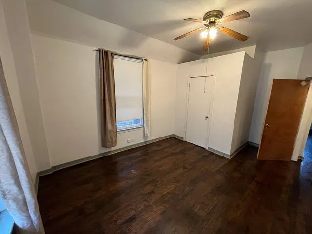 an empty room with wooden floor and fan