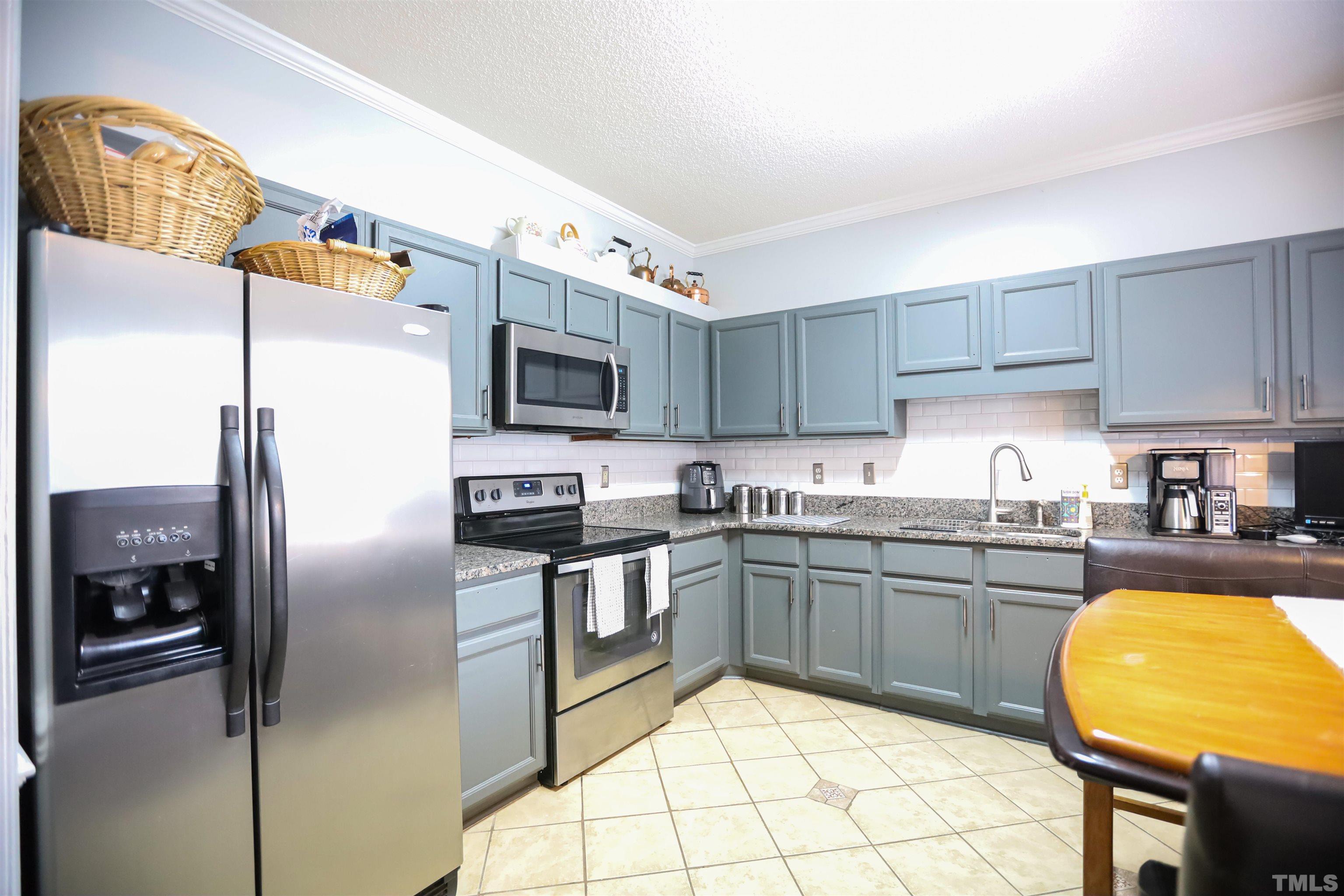 4102 Beaufain Street Raleigh, NC 27604 - Photo 13 of 28 a kitchen with stainless steel appliances granite countertop a sink a stove a chimney a refrigerator and cabinets