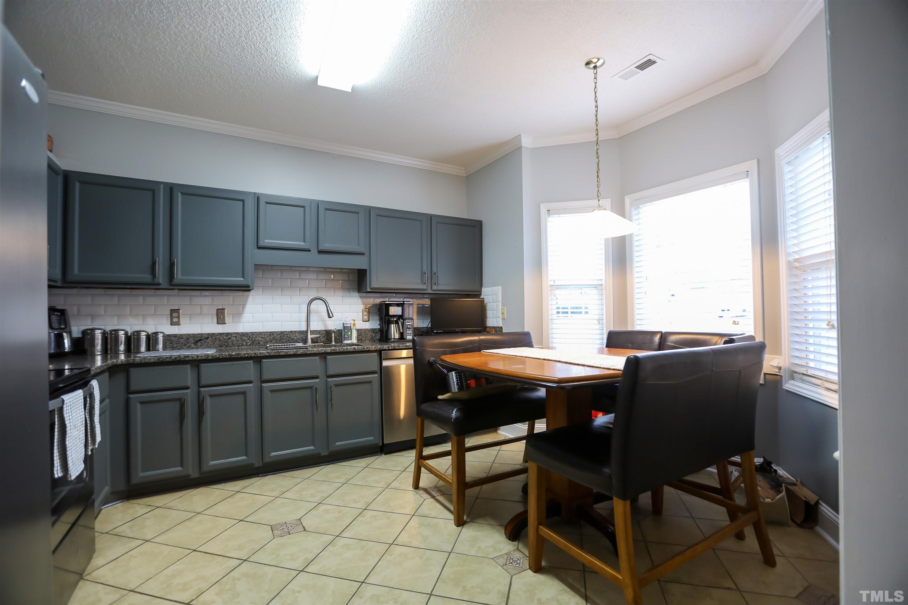 4102 Beaufain Street Raleigh, NC 27604 - Photo 14 of 28 a kitchen with stainless steel appliances granite countertop a stove top oven a sink dishwasher a dining table and chairs with wooden floor