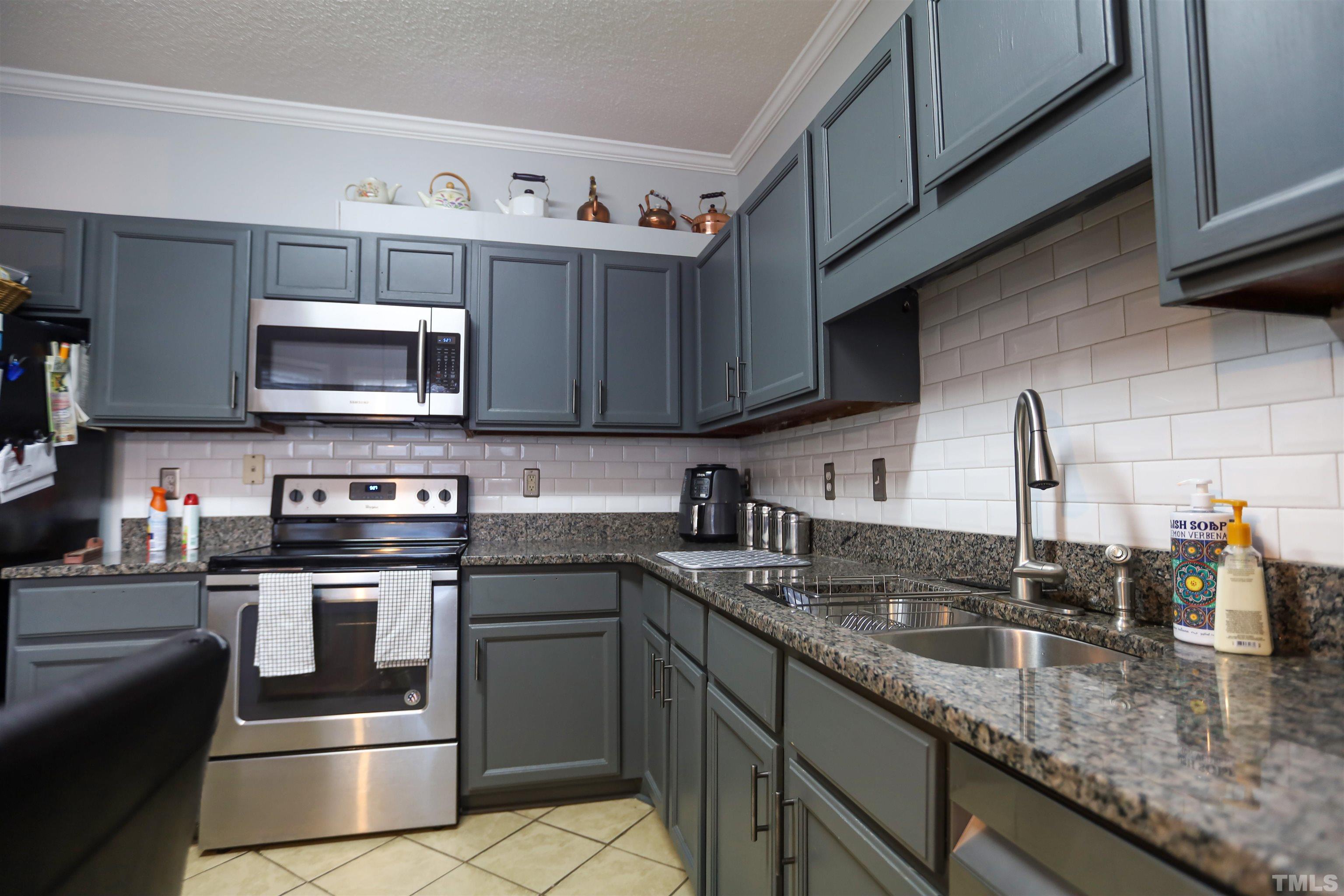 4102 Beaufain Street Raleigh, NC 27604 - Photo 15 of 28 a kitchen with stainless steel appliances granite countertop a sink stove and microwave