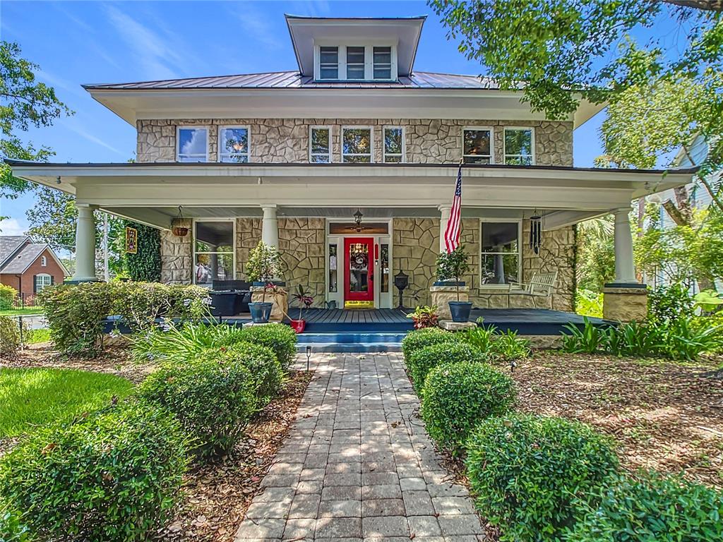 a view of a brick house with large windows and plants
