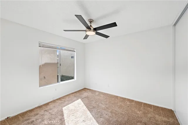 an empty room with a window and a ceiling fan