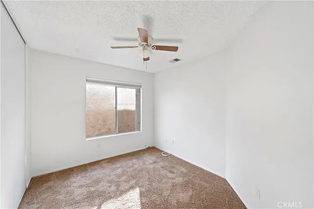 an empty room with windows and fan