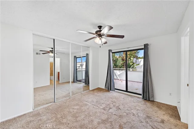 an empty room with chandelier fan and windows