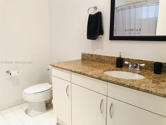 a bathroom with a granite countertop sink a mirror and toilet