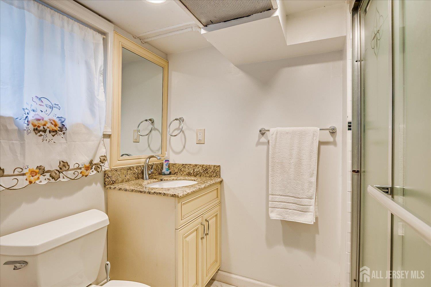 311 Prospect Avenue Dunellen, NJ 08812 - Photo 23 of 42 a bathroom with a granite countertop sink a toilet a mirror and shower
