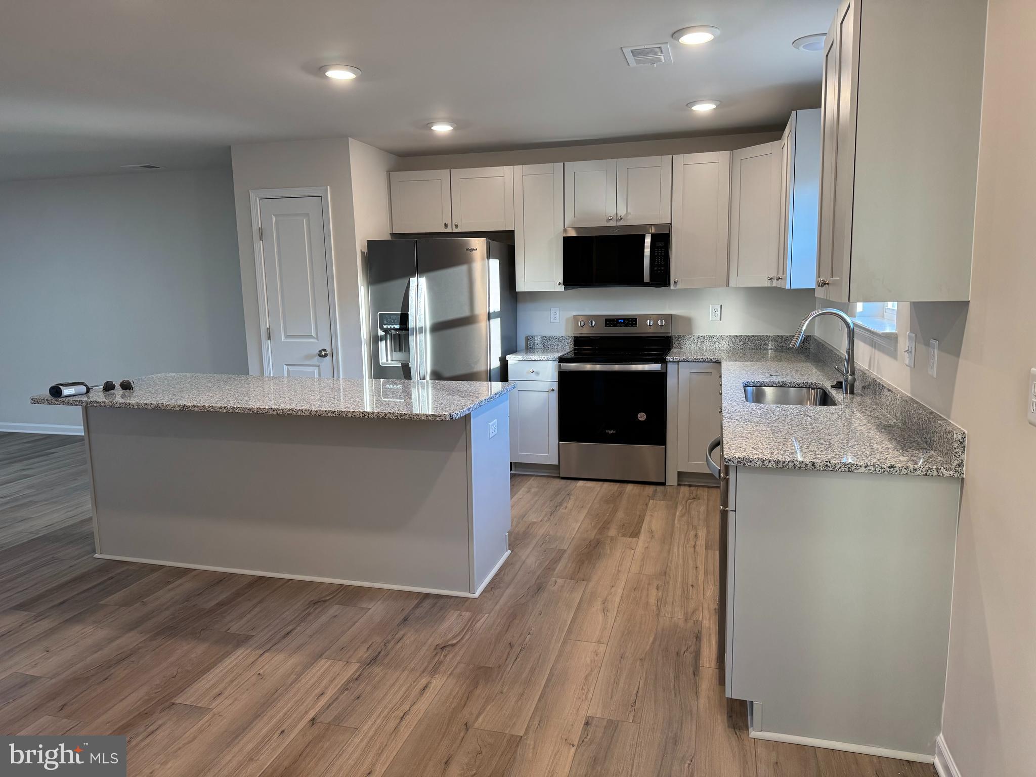 657 R Wilson Loop Georgetown, DE 19947 - Photo 3 of 7 a kitchen with stainless steel appliances granite countertop a refrigerator a stove top oven a sink and dishwasher with wooden floor