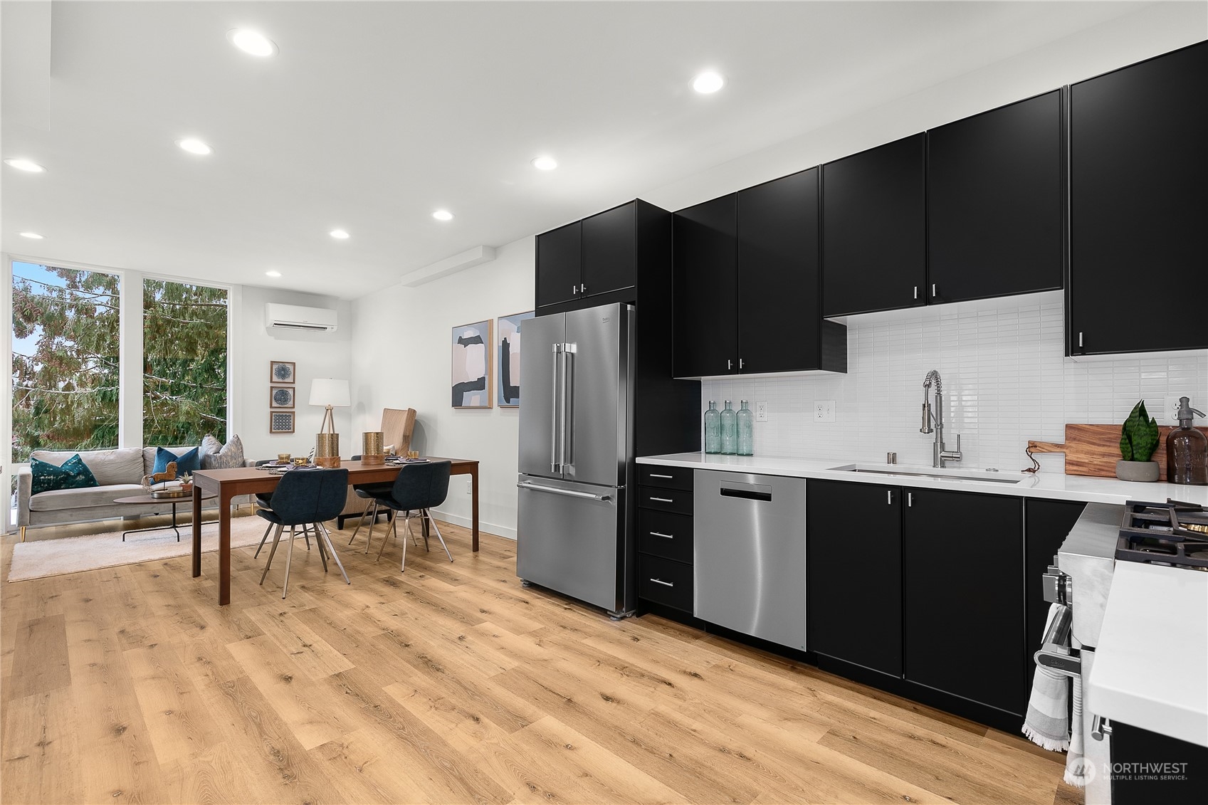 9429 18th Avenue Southwest, Unit B Seattle, WA 98106 - Photo 10 of 28 a kitchen with kitchen island wooden cabinets a refrigerator a stove a sink and a dining table with wooden floor