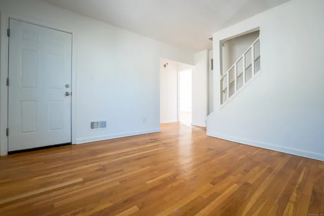 a view of an empty room with wooden floor and stairs