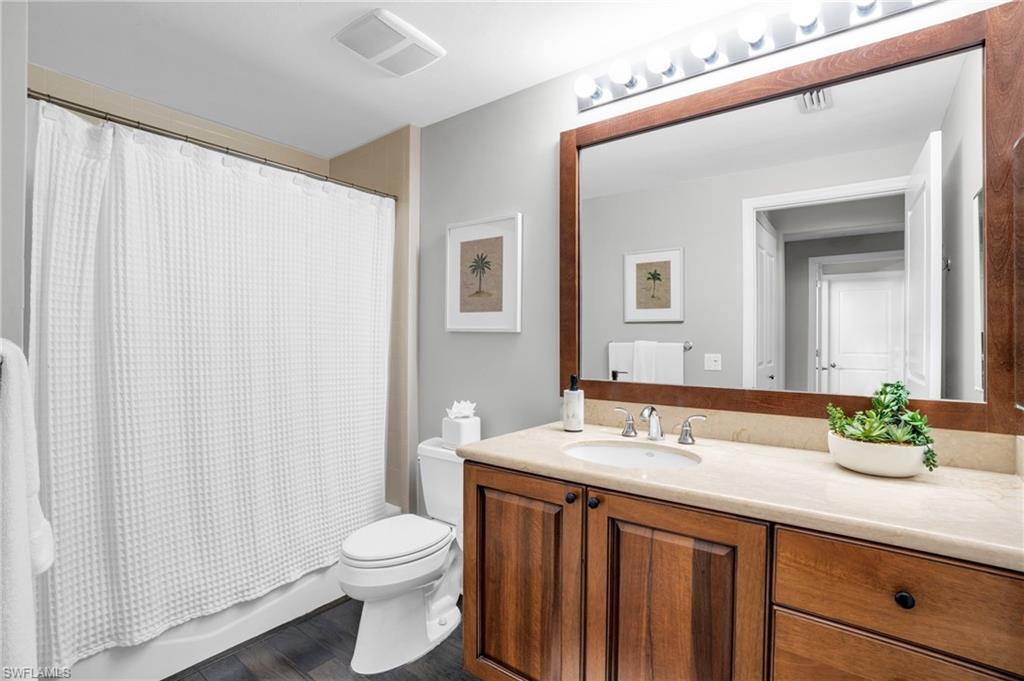 985 Sandpiper Street, Unit I103 Naples, FL 34102 - Photo 14 of 32 a bathroom with a granite countertop sink a toilet and a mirror