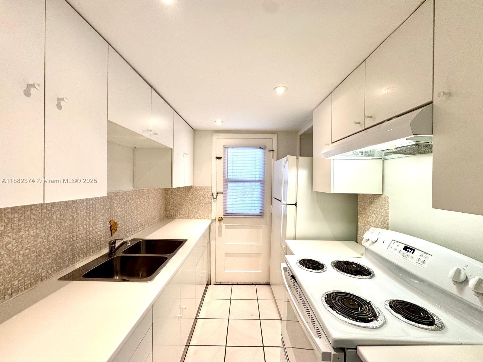 1475 Northeast 125th Terrace, Unit 404B North Miami, FL 33161 - Photo 12 of 22 a kitchen with a sink a stove and a refrigerator