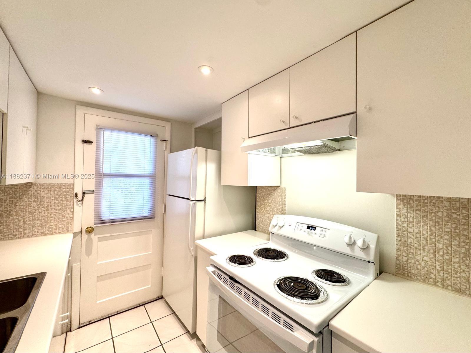 1475 Northeast 125th Terrace, Unit 404B North Miami, FL 33161 - Photo 14 of 22 a kitchen with a stove a refrigerator and a cabinets