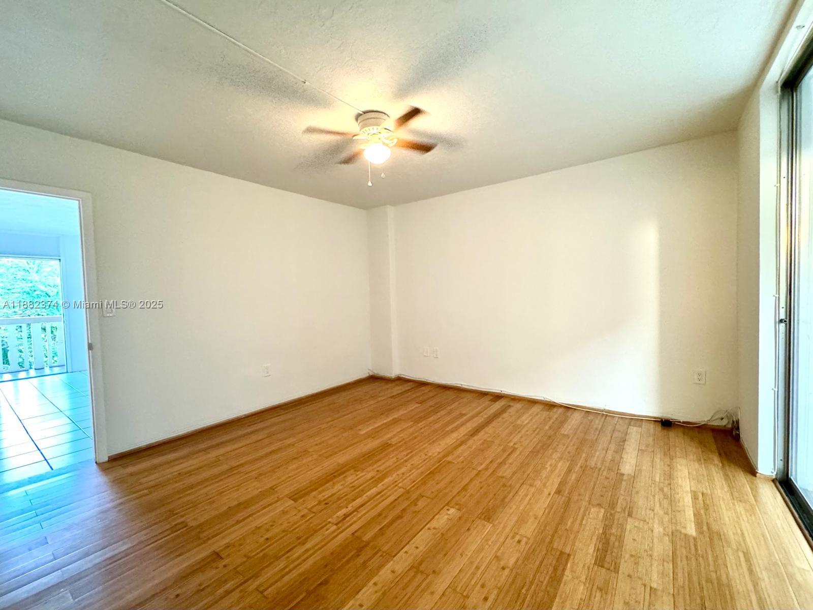 1475 Northeast 125th Terrace, Unit 404B North Miami, FL 33161 - Photo 5 of 22 an empty room with wooden floor and windows
