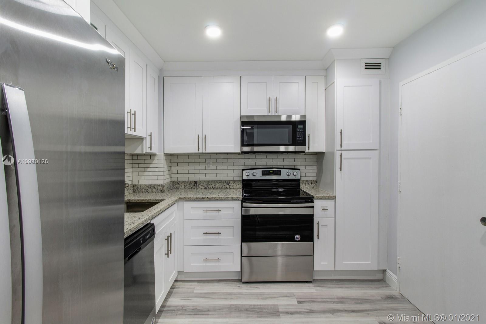 Newly designed kitchen features white cabinets, granite countertops, subway tile backsplash and stainless steel appliances.