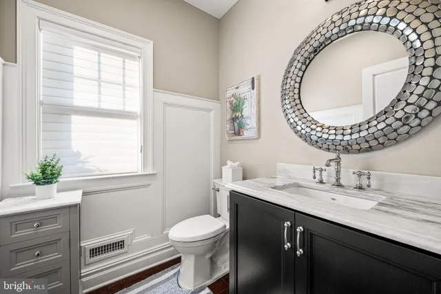 a bathroom with a granite countertop toilet sink mirror and window