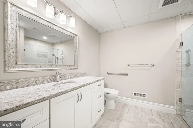 a bathroom with a granite countertop sink a toilet and a mirror