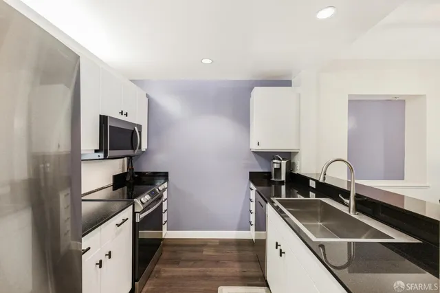a kitchen with granite countertop a sink stainless steel appliances and cabinets