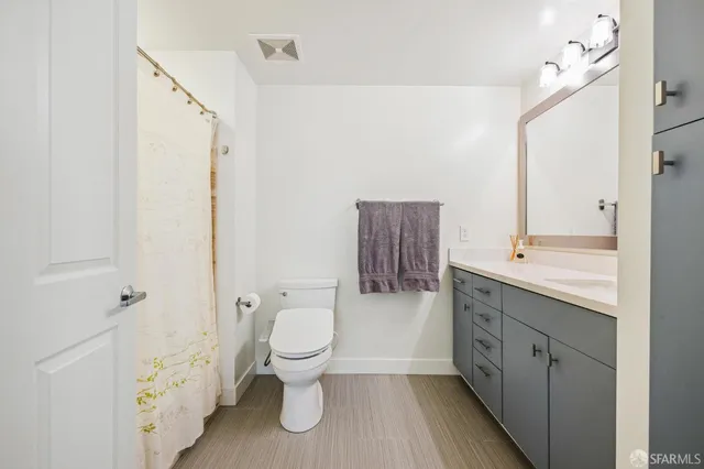 a bathroom with a granite countertop toilet a sink and a mirror