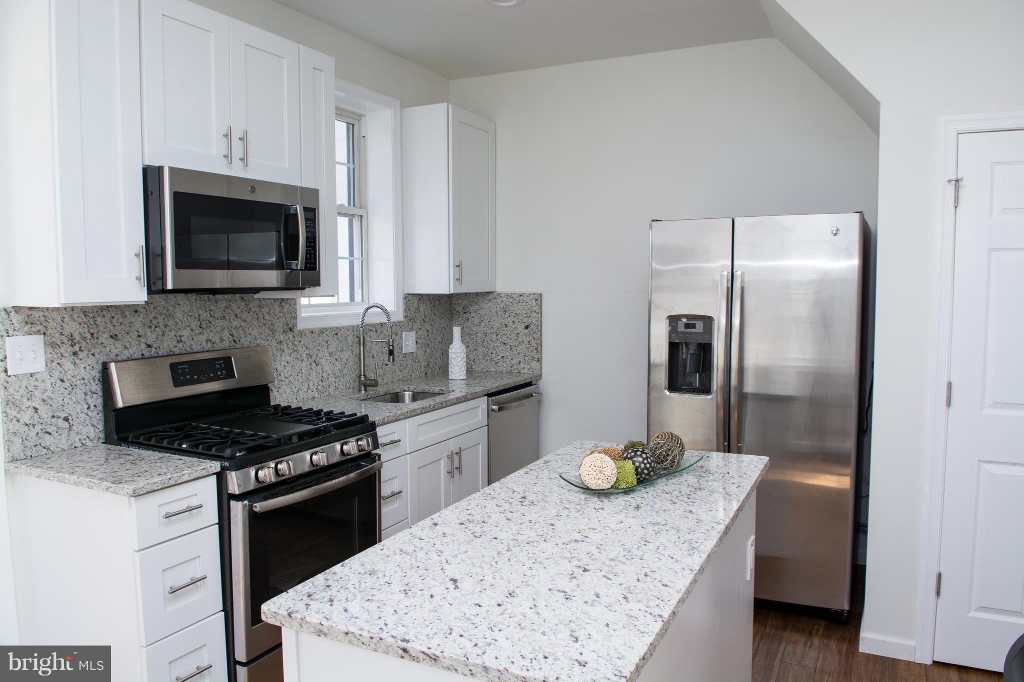6216 5th Street Northwest Washington, DC 20011 - Photo 7 of 25 a kitchen with stainless steel appliances kitchen island granite countertop a refrigerator a stove and a sink