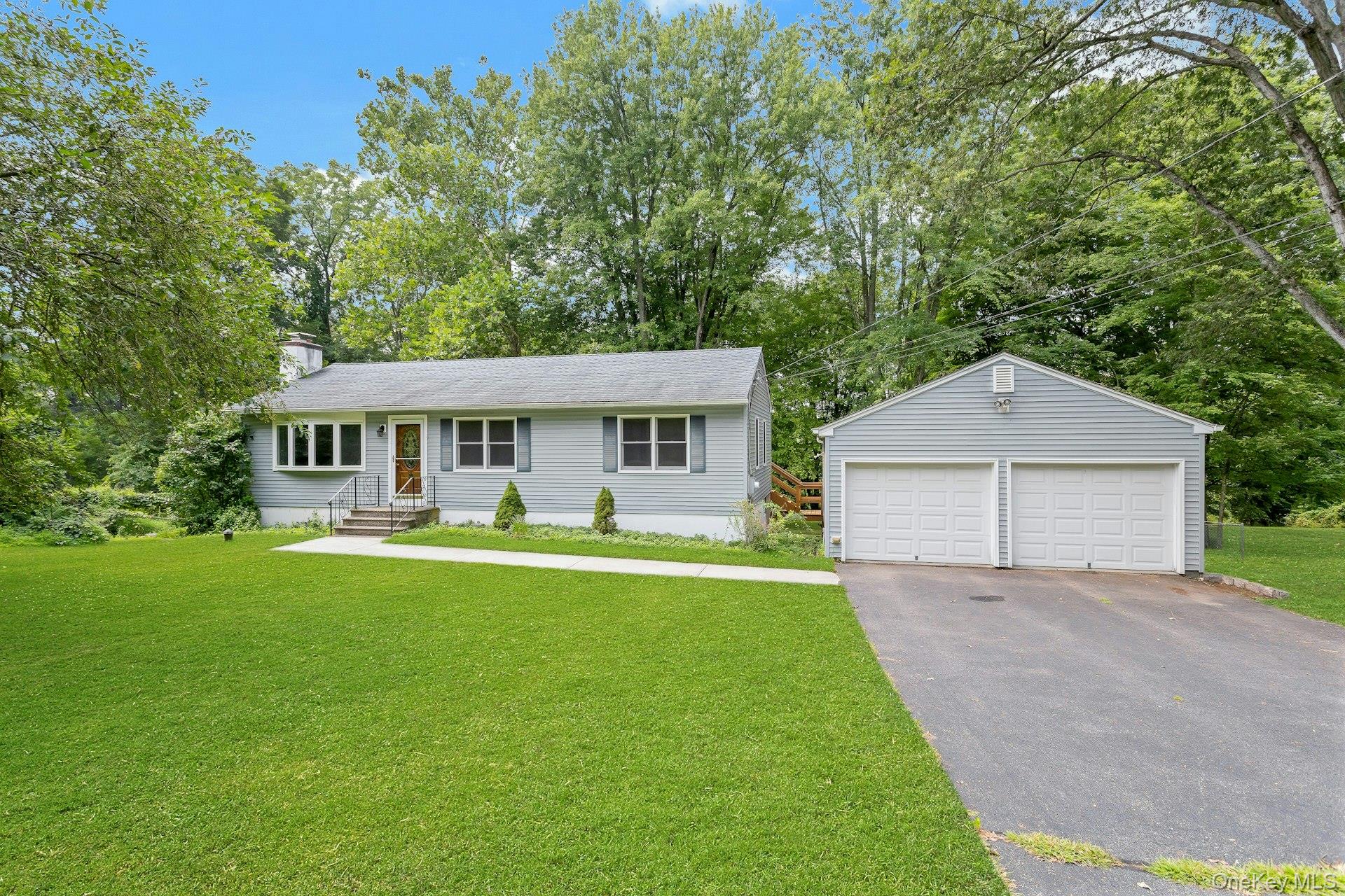 67 Reed Road Brewster, NY 10509 - Photo 1 of 1 Ranch-style house featuring view of wooded area, a detached garage, an outbuilding, a front yard, and a chimney