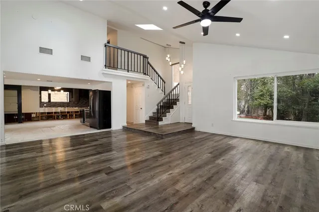 an empty room with wooden floor a ceiling fan and windows