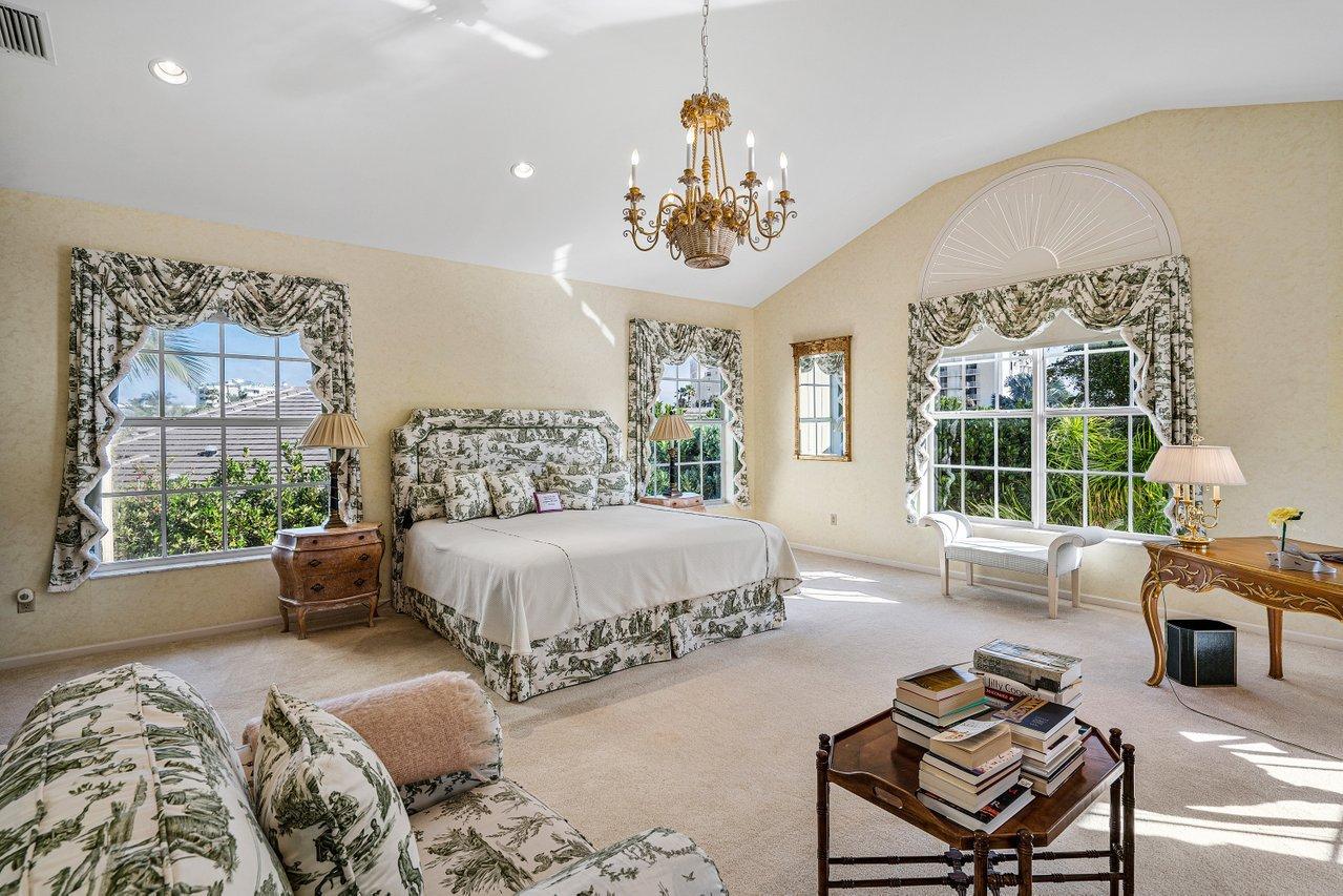 169 Apollo Circle Jupiter, FL 33477 - Photo 38 of 54 a spacious bedroom with a large bed and a chandelier