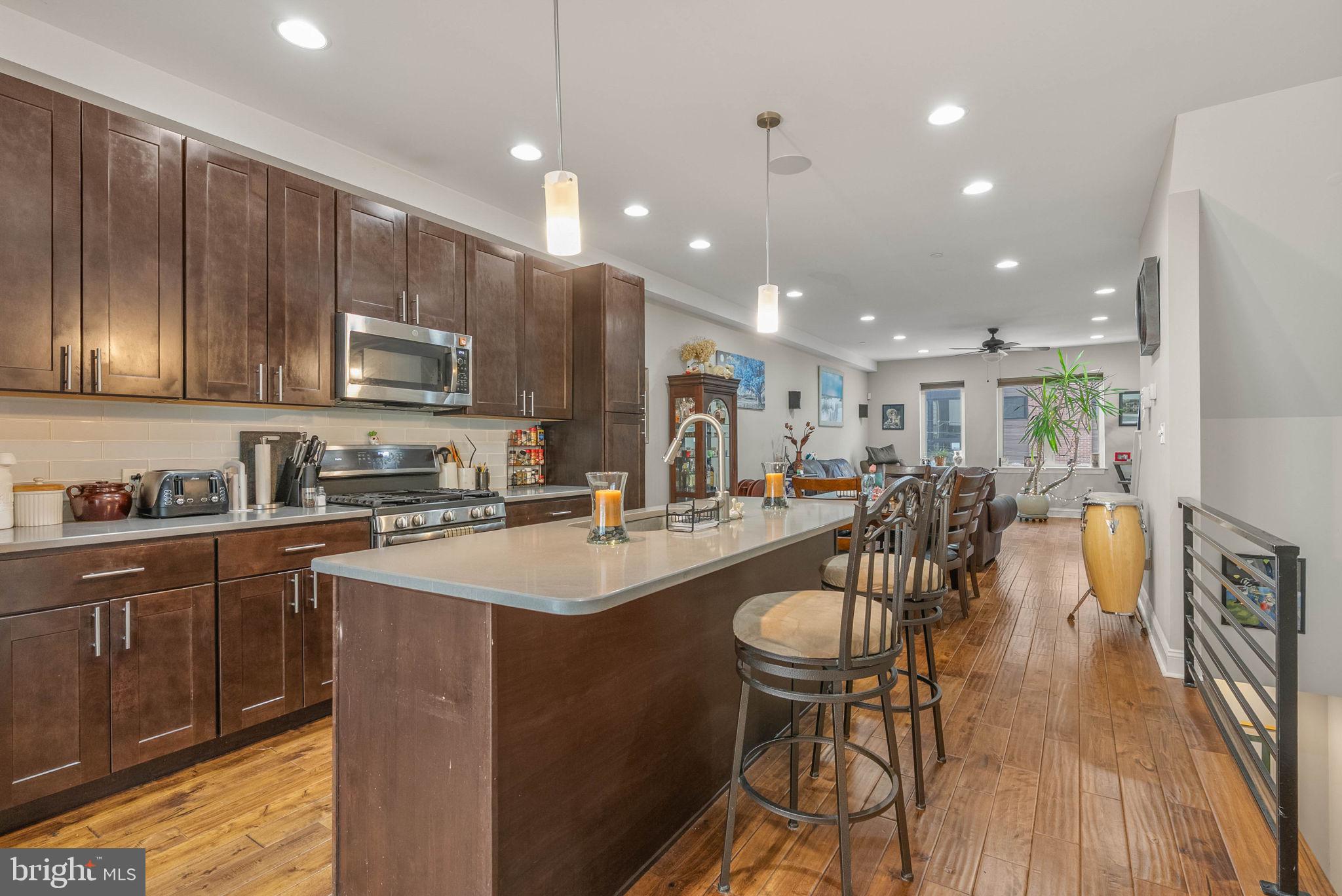 1423 South Howard Street Philadelphia, PA 19147 - Photo 12 of 40 a kitchen with stainless steel appliances kitchen island granite countertop a stove a sink a refrigerator and a dining table with wooden floor