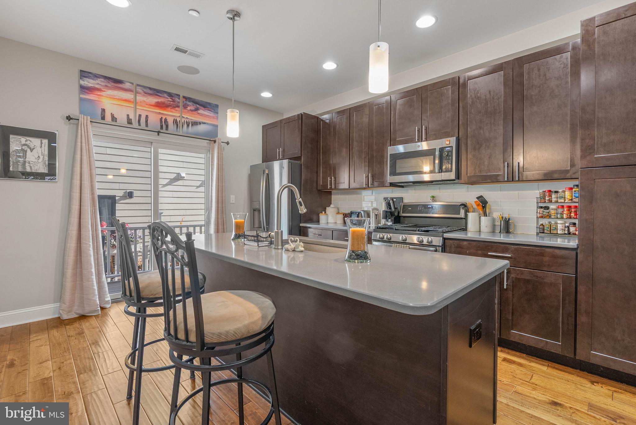 1423 South Howard Street Philadelphia, PA 19147 - Photo 15 of 40 a kitchen with kitchen island granite countertop a table chairs microwave and cabinets