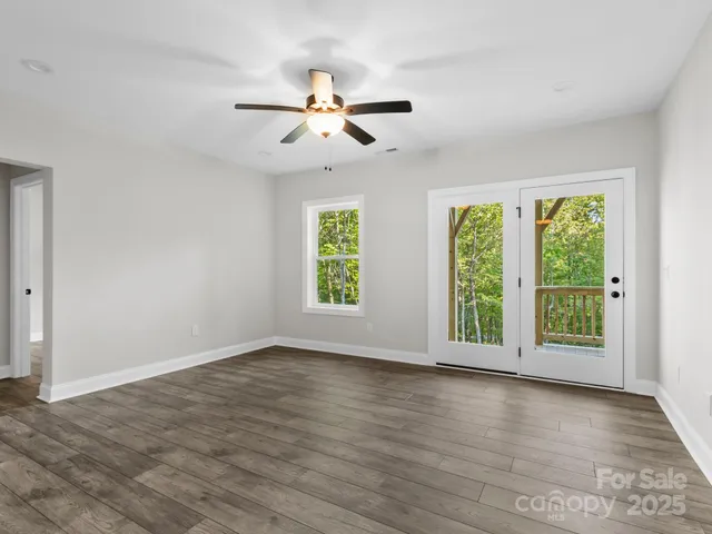 an empty room with wooden floor cabinet and windows