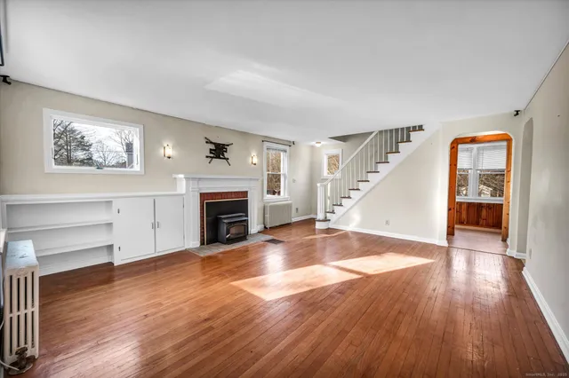 an empty room with wooden floor fireplace and windows