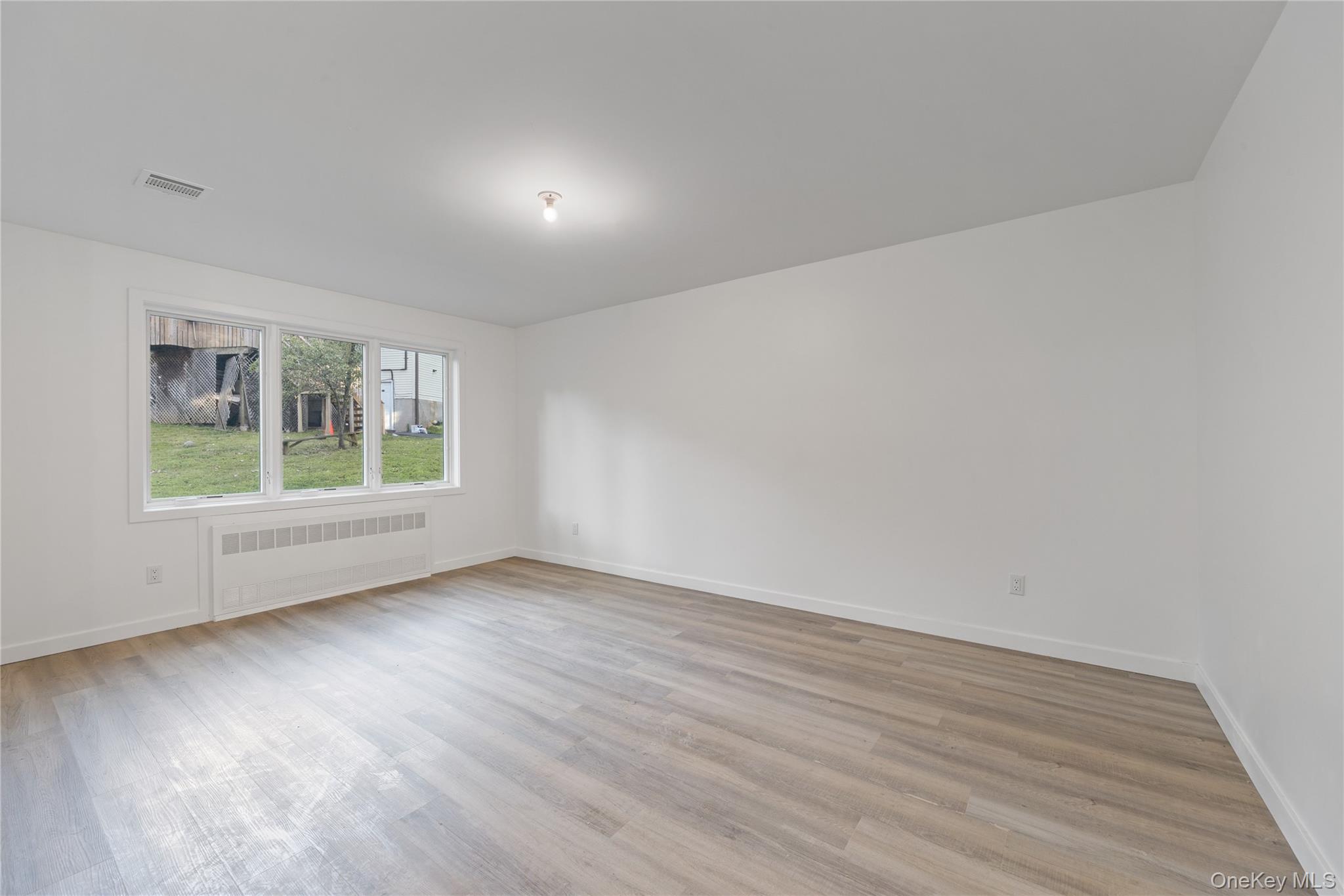 40 Singer Avenue, Unit 214 Spring Valley, NY 10977 - Photo 41 of 49 a view of an empty room with wooden floor and a window