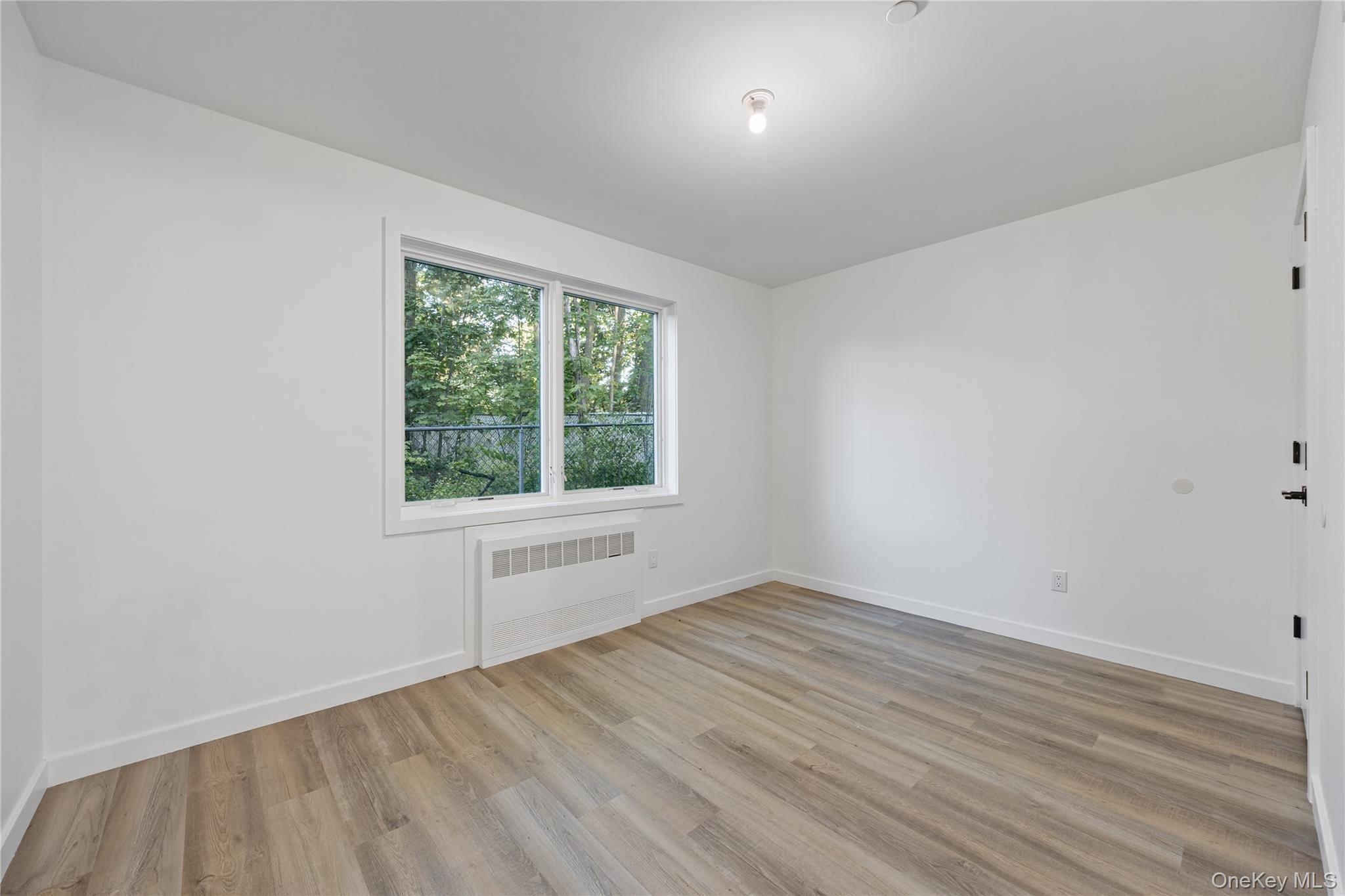40 Singer Avenue, Unit 214 Spring Valley, NY 10977 - Photo 48 of 49 an empty room with wooden floor and windows