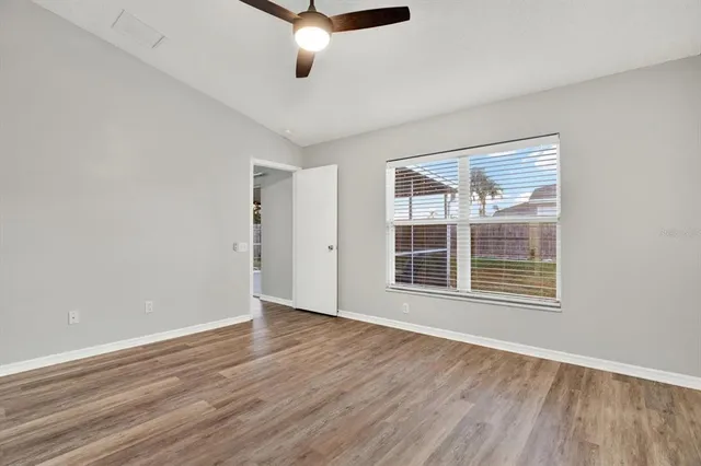 a view of an empty room with wooden floor and a window