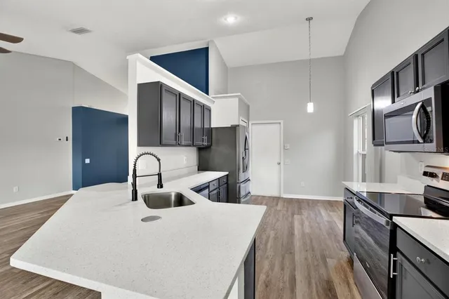 a kitchen with kitchen island stainless steel appliances a sink stove and refrigerator