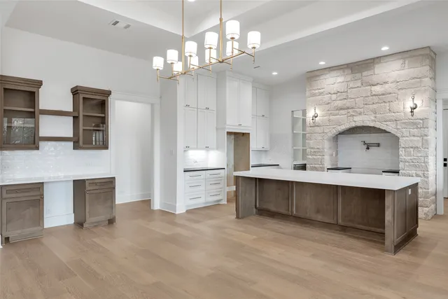 a large white kitchen with a sink and chandelier