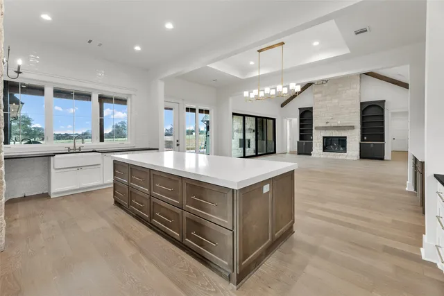 a large white kitchen with a large island oven a sink stainless steel appliances and cabinets