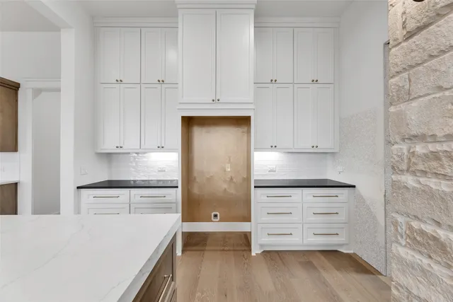 a kitchen with granite countertop white cabinets and stainless steel appliances