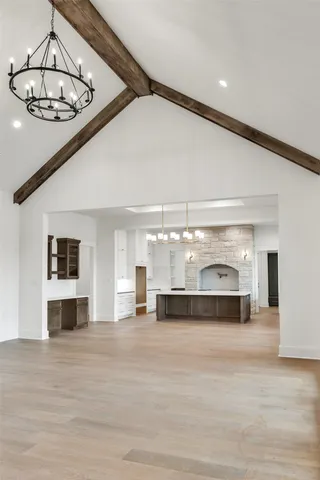 a view of a living room a kitchen island stainless steel appliances wooden floor and chandelier