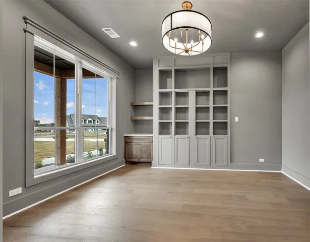 a view of an empty room with a window and a kitchen
