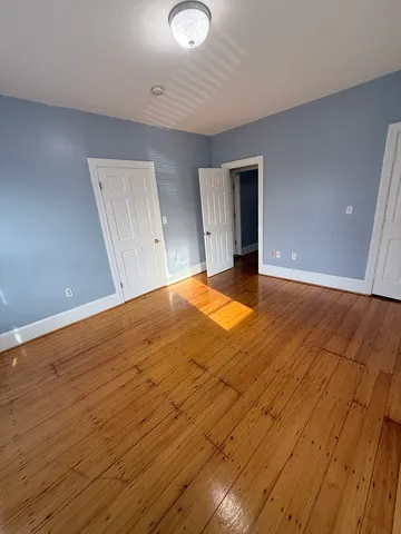 a view of an empty room with wooden floor and closet