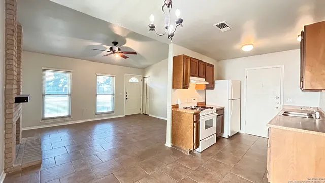 a kitchen with stainless steel appliances granite countertop a stove top oven a refrigerator a sink dishwasher with a dining table and chairs