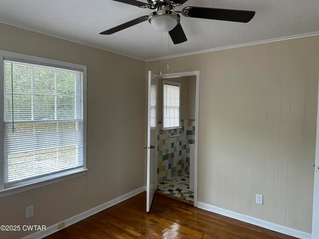 a view of empty room with wooden floor and fan