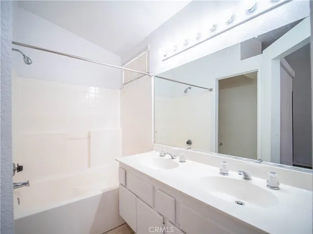 a bathroom with a bathtub shower sink vanity and mirror