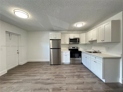 a kitchen with refrigerator a microwave a sink and cabinets
